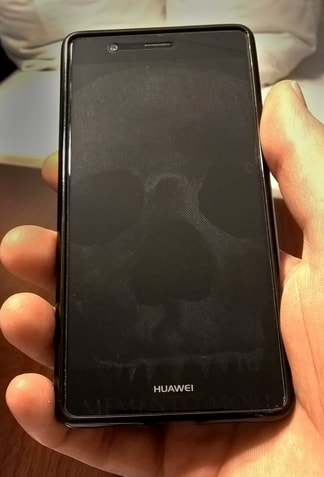 Image of a mobile phone whose glass screen has been subtly engraved with an image of a skull.